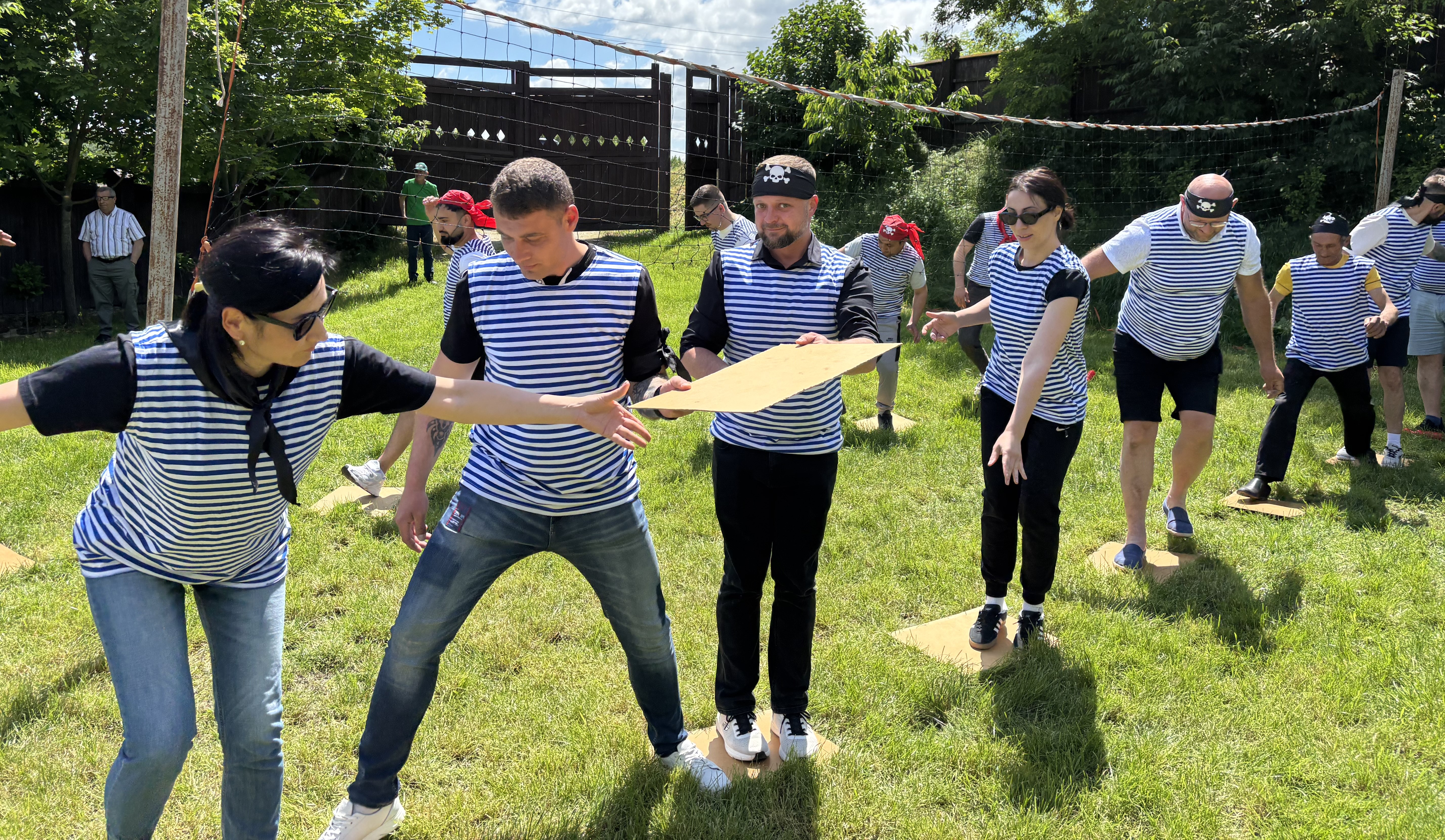 Angajați traversând un obstacol în echipă în cadrul provocării Podul Piraților test de echilibru și colaborare